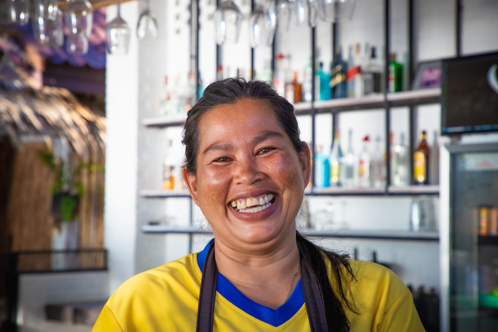 เจ้าของร้านหญิงหัวเราะอย่างมีความสุขหน้าเคาน์เตอร์บาร์ของร้านตัวเอง